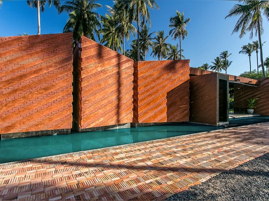 Les plantations de noix de coco entourent la maison de retraite de brique sur une plage thaïe par le studio de NPDA