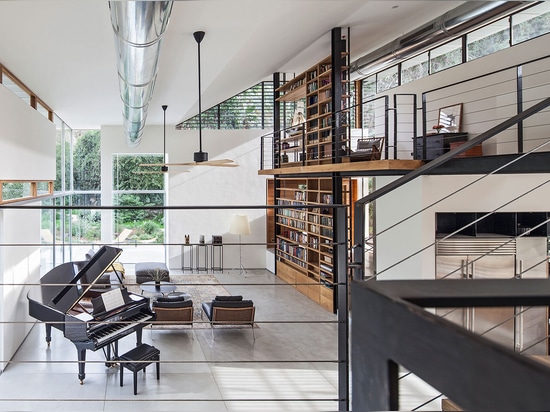 L'espace également comporte une bibliothèque de double taille et est donné sur par un couloir de mezzanine qui enroule autour des murs de salle de séjour sur le premier étage