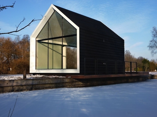 La cabine minuscule en verre et de bois de construction se plie abilement ouvert pour se mélanger dedans avec le paysage néerlandais