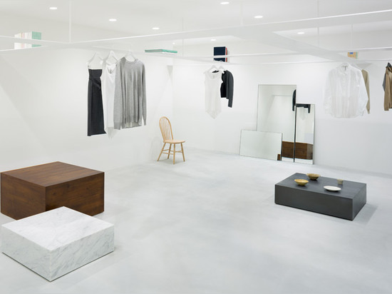 La grille de Nendo des étagères suspendues accroche au-dessus des clients dans la boutique beige de mode