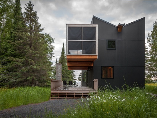 La galerie de bois de construction se repose au-dessus de la véranda de la retraite du bord de lac de l'architecte de Salmela