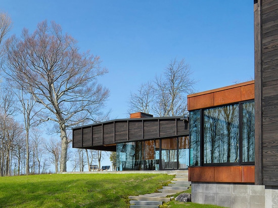 le chia de desai unit trois structures excentrées pour former la maison carbonisée de lac de bois de construction au Michigan