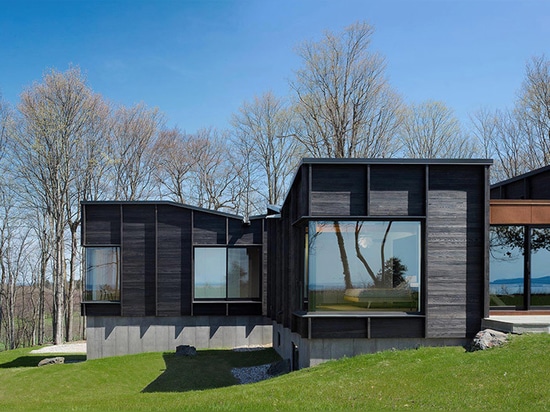 le chia de desai unit trois structures excentrées pour former la maison carbonisée de lac de bois de construction au Michigan