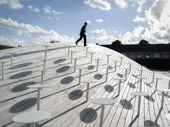 Extérieurement le toit de gonflement du gymnase forme un nouveau paysage, pointillé avec l'allocation des places conçue pour encourager l'intégration sociale. Photographie : Jens Lindhe