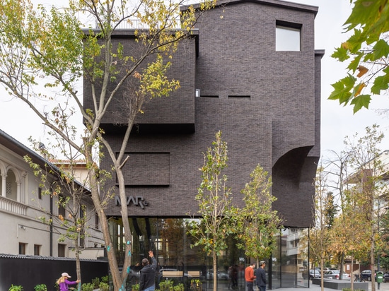 La YTAA transforme une vieille villa en un musée avec des surfaces irrégulières sombres et une base vitrée à Bucarest