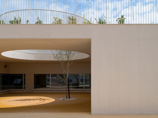 Des trous circulaires relient les terrains de jeux sur deux niveaux d'une école de Lisbonne