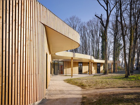 La façade curvaceous est plaquée dans les bandes des lattes verticales du mélèze laissées non traitées pour imiter les troncs du paysage de régfion boisée.