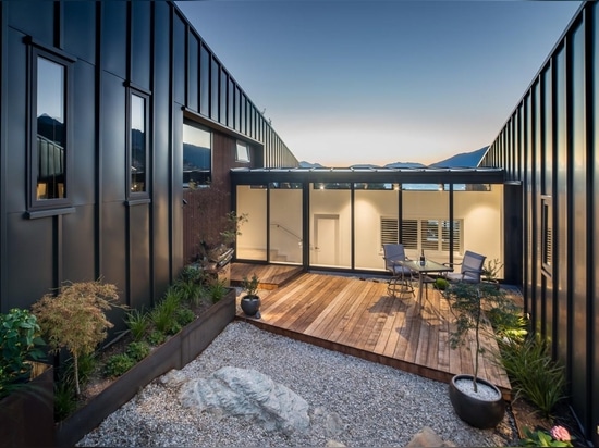 Cette maison à flanc de colline avec un revêtement métallique noir a été conçue pour maximiser la vue sur le lac