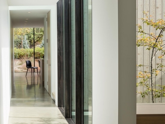 Un bureau à domicile a été rendu possible par la construction d'un bureau le long d'un mur de fenêtres à l'intérieur de cette maison