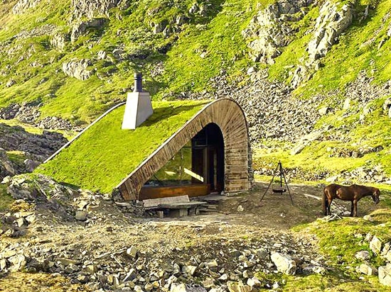 La carlingue minuscule renversante se tient le long d'un lac, entre les crêtes norvégiennes élevées.