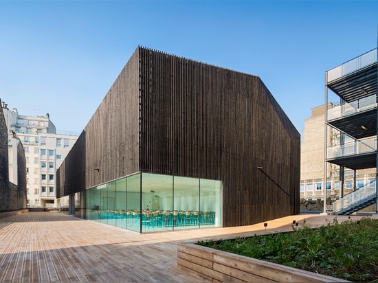 la structure est plaquée en lamelles foncées de bois de construction, prenant la forme d'une grange rurale