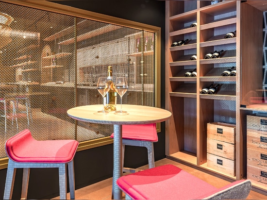 Un espace de dégustation de vin contemporain utilise le treillis métallique en laiton M22-83 comme séparateur d'espace pour une salle de dégustation.