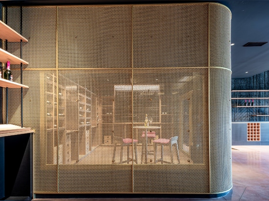 Un espace de dégustation de vin contemporain utilise le treillis métallique en laiton M22-83 comme séparateur d'espace pour une salle de dégustation.