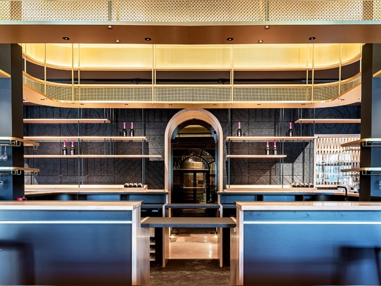 Un espace de dégustation de vin contemporain est doté d'un portique de plafond en treillis métallique en laiton M22-83 qui forme une voûte sculpturale au-dessus du bar.