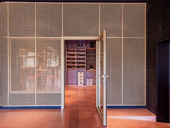 Un espace de dégustation de vin contemporain utilise le treillis métallique en laiton M22-83 comme séparateur d'espace pour une salle de dégustation.