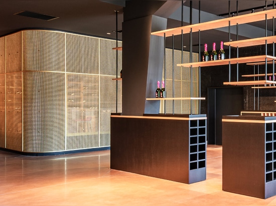 Un espace de dégustation de vin contemporain utilise le treillis métallique en laiton M22-83 comme séparateur d'espace pour une salle de dégustation.